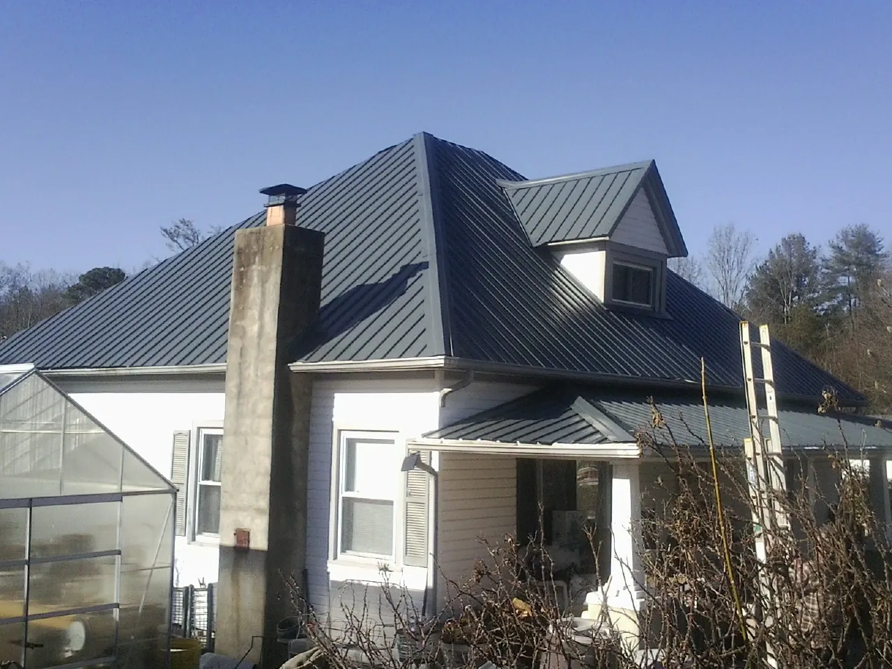 Dark blue standing seam metal roof on a white farmhouse with dormer — Slate & Tile Roof Repair by Roofing Brothers in Carleton