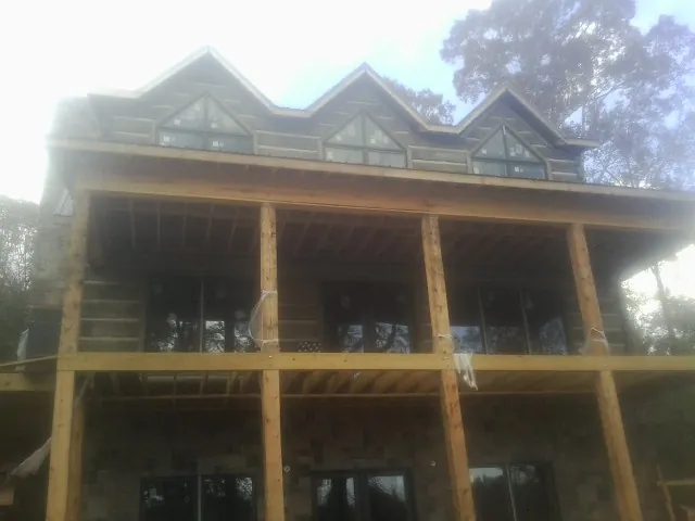 Dormers and porch framing on a large log home under construction — Roof Coating work by our crew in Carleton