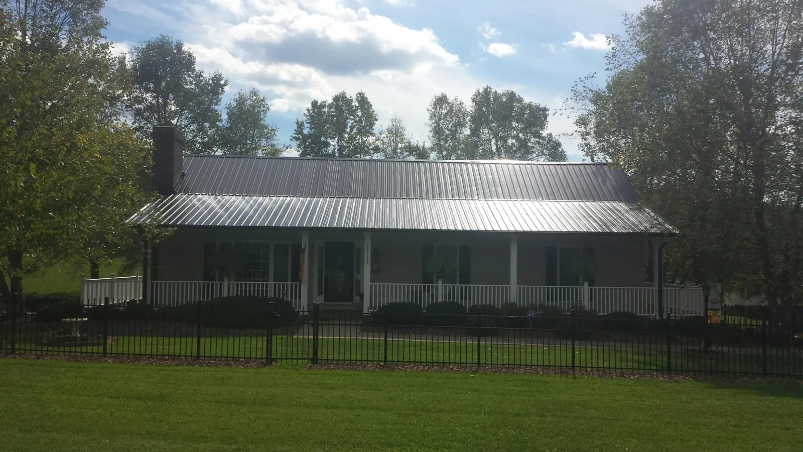 Gray metal roof on a brick ranch with a full width front porch — Gutter Guard Installation work by our crew in Carleton